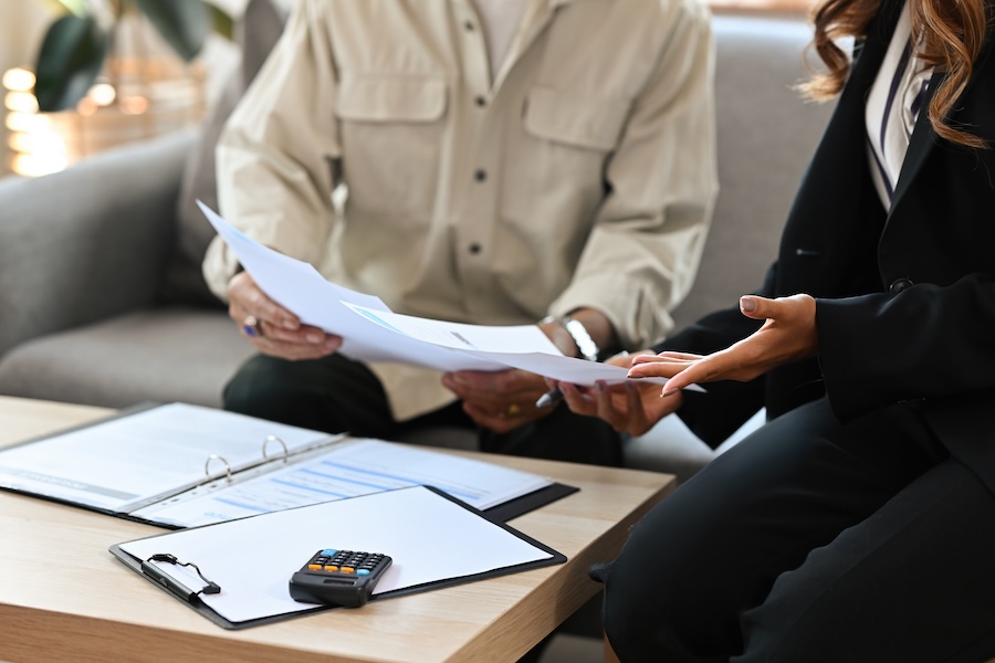 2 people sitting on a couch in a house going over paperwork.